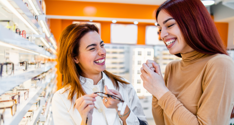 patient and optometrist selecting glasses at eye doctors office, smiling