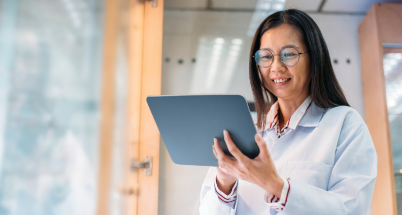 A female optometrist smiling and looking at a tablet 