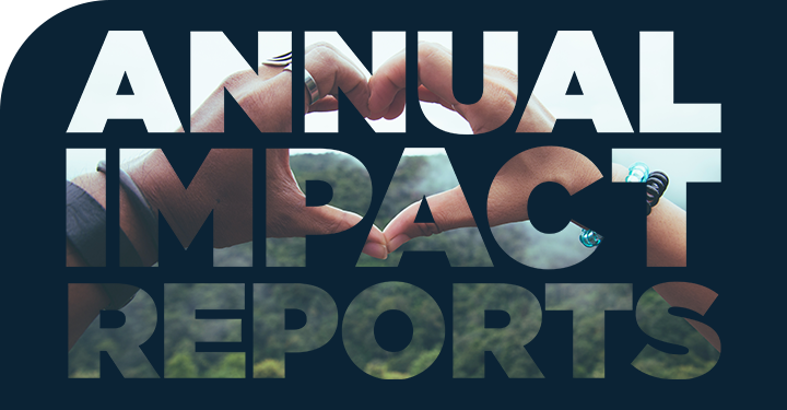 "Annual Impact Reports" in transparent text over an image of hands placed together in the shape of a heart surrounded by dark blue