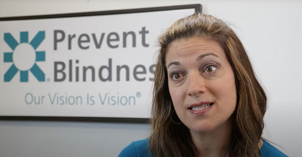 A women standing beside a Prevent Blindness sign