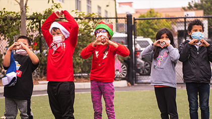 Children from Monarch School making a heart with hands 